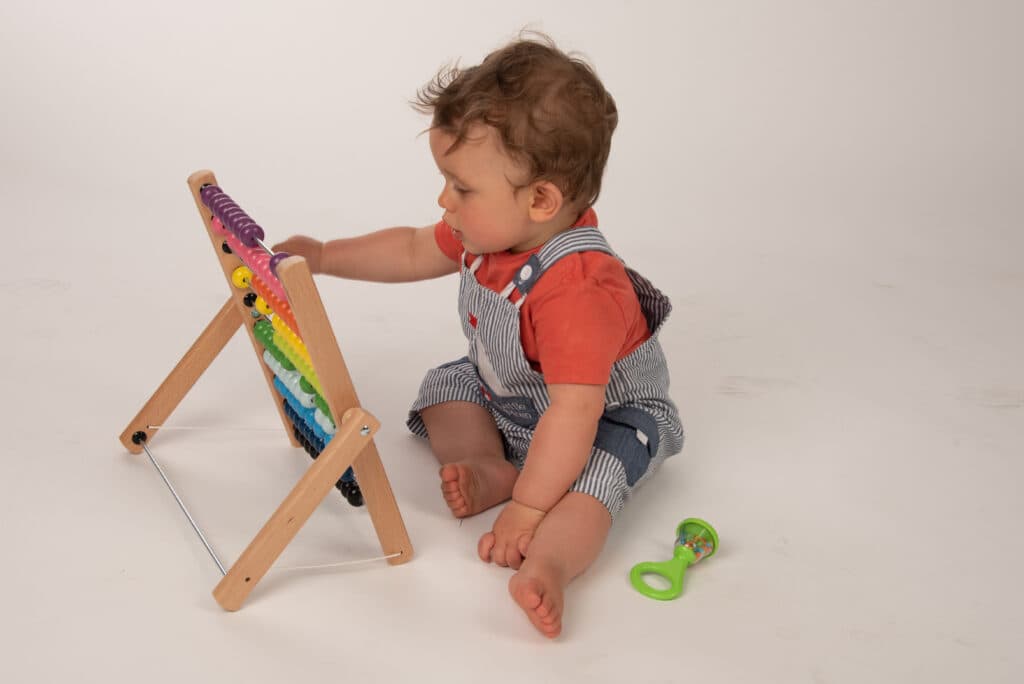 Jeune enfant en éveil avec un jeu en bois — Co Né Sens